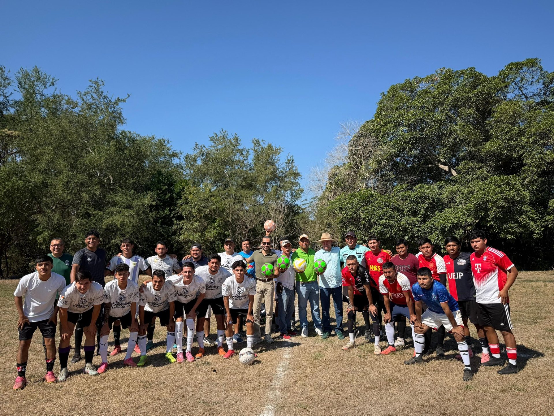 Equipo de fútbol comunitario reunido durante una entrega de balones en una zona rural